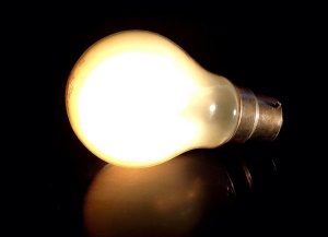 Image shows an illuminated lightbulb against a black back ground.